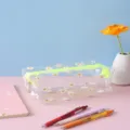 Detailed view of clear daisy printed pencil case with bright zipper in aesthetic desk setup. - White Floral