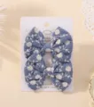 Pair of blue fabric bow hair clips with white floral daisy embroidery on white card - Daisy Embroidered Bow (30)