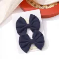 Pair of navy blue embroidered fabric bow hair clips for girls on a white display card - Embroidered Bow Hair Clip (7)