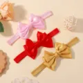 Vue détaillée de trois bandeaux pour bébé avec nœuds en satin élégants en rose, rouge et doré - 3 Pièces/Paquet / Couleurs Mélangées (3C)