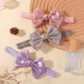 Gros plan de trois bandeaux bébé avec nœuds en satin rose, argenté et lavande - 3 Pièces/Paquet / Couleurs Mélangées (3E)