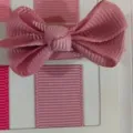 Close-up view of a small pink grosgrain ribbon bow hair clip for babies and girls - Pink