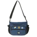 Close-up detail of a navy blue canvas messenger bag featuring decorative badges - With Badges / Blue