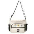 Front view of cream utility messenger bag featuring decorative badges and logo patch - With Badges / White