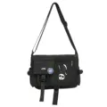 Close-up of black nylon messenger bag with utility pockets and streetwear patches - Messenger Bag (Includes Badges) / Black