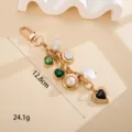 Detailed macro view of vintage gold keychain with heart and emerald stone charms, 12.8cm long. - 方块宝石加花纹爱心挂件