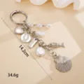 Detailed view of the ocean-themed zinc alloy keychain with shell and pearl charms. - 贝壳加小鱼挂件 / Silver