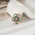 Primo piano di un ciondolo camelia blu fai-da-te con base dorata e dettagli in cristallo. - Stile Camelia (D3447) / 22mm / Azzurro