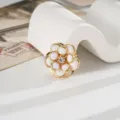 Macro di un ciondolo a camelia bianca con bordo dorato e strass centrale - Bianco