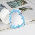 Close-up detail of blue liquid fluid mirror frame with pink gemstones for DIY phone cases. - Blue
