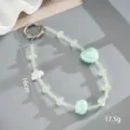 Gedetailleerde macro-opname van een groene acryl kralen telefoonkoord met hart en strik - Telefoonaccessoire (K6424) / Wolk Strik Hart Hanger Groen
