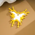 Close-up detail of yellow irregular butterfly mirror charm with clear gemstones on leather background - Yellow
