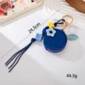 Gros plan du mini porte-monnaie en cuir bleu avec détails d'étoiles et pompon - Pendentif Myrtille (K6112)