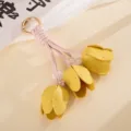 Nahaufnahme von drei gelben Leder-Tulpenknospen an einem rosa gewebten Taschenanhänger - 郁金香皮革挂件(K6354)
