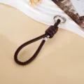 Detail of handmade woven dark brown leather rope keychain with silver bead and knot - Dark Coffee