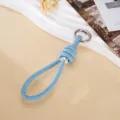 Close-up detail of light blue handmade leather woven keychain with silver bead and metal clasp - Blue