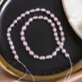 Close-up detail of 5-6mm purple freshwater rice pearls on black plate for DIY jewelry making. - One Strand Length 35cm Around 45 Pieces / Natural Purple