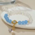 Nahaufnahme Detail des chinesischen Perlenarmbands mit blauen Steinen und goldenem Anhänger. - Süßwasserperle Aquamarin Weißer Jade (B4217)