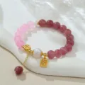 Gros plan détaillé d'un bracelet en perles naturelles, agate rose et breloques dorées de style chinois. - Perle Naturelle Cristal Rose (B4190) / Diamètre de la perle environ 8 mm