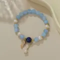 Nahaufnahme eines handgefertigten Perlen- und Kristall-Perlenarmbands mit Feder-Anhänger. - Süßwasserperle Hellblauer Achat (B4272)