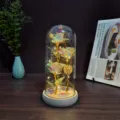 Detailed view of the enchanting gold foil rose night light inside a clear glass dome on a wooden base. - Glass Dome with USB / Multi-Color Gold