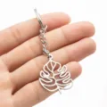 Close-up of a stainless steel monstera leaf keychain pendant held in a hand clearly. - Steel