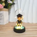 Close-up detail of graduation acrylic dome night light with LED base and cute figurine. - Male Graduate Style / Acrylic Dome