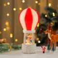 Christmas snow globe detail featuring the cute snowman figurine inside the decorative balloon. - Snowman Hugging Tree Child