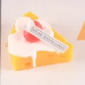 Detailed close-up view of the cute cheese cake scented candle featuring cream and red cherry. - Cherry Cheesecake
