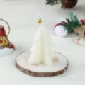 White Christmas tree scented candle with bell detail, perfect holiday decorative wax piece. - Triangle Christmas Tree