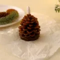 Close-up view of a detailed pine cone shaped wax candle with warm festive atmosphere props. - Regular 2 Pack Small Solid Brown