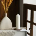 Detailed close-up of a white striped pillar candle on wooden base with rustic decor scene. - White Pointed Fine Ribbed 5*17.5