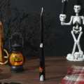 Halloween scented taper candle detail view featuring cute ghost and pumpkin print on black wax. - Black