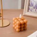 Primer plano detallado de una vela de cubo creativa con llama blanca para decoracion. - Vela cubo bala color café