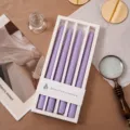 Detailansicht von 4er-Set lila Duftkerzen im Stabkerzen-Design in weißer Geschenkbox. - Hellviolett (Lavendel & Thymian)
