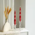 Detail view of red twisted long soy wax candles in clear glass holders with wheat deco. - Bright Red