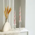 Detail view of pink twisted scented soy wax pillar candles with clear glass candle holders. - Pink