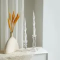 Detailed view of twisted white scented soy candles in clear glass candle holders with vase setup. - White
