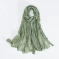 Detailed view of a sage green crinkled voile scarf, soft sheer fabric texture closeup. - Mint Green