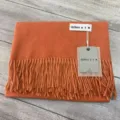 Vue détaillée du doux foulard d'hiver en cachemire mélangé avec franges et étiquette. - Écharpe châle orange