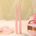 Gros plan de deux bougies roses fines avec une radio rétro décorative sous un éclairage chaleureux. - Longue Tige Cœur / Lot de 2 / Rose