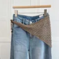 Vue détaillée d'un foulard triangulaire au crochet fait main avec un pantalon en jean. - Châle foulard en tricot ajouré kaki