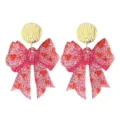 Gros plan de boucles d'oreilles nœud à paillettes roses étincelantes avec clous ronds dorés. - Style Nœud Rose (25101301)