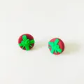 Nahaufnahme der handgefertigten Fimo-Weihnachtsgeschenkbox-Ohrstecker mit grüner Schleife. - Rot-Grün-Kombination