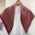 Vista dettagliata del foulard in seta triangolare bordeaux classico, drappeggiato su camicia. - Sciarpa a triangolo rosso vino con lettere