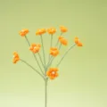 Nahaufnahme einer handgehäkelten orangen Blume mit Perlzentrum am grünen Stiel, Detail. - Orange