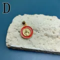 Ciondolo in metallo dorato con smalto rosso e motivo religioso classico in primo piano. - Stile D