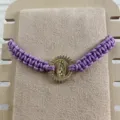 Close-up detail of the purple braided rope bracelet featuring a gold Guadalupe rhinestone charm. - Purple