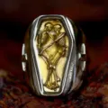 Close-up detail of gothic retro coffin ring featuring dual skeleton design and cross accents. - US Size 7 / Gold Embossing
