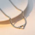Close up of a silver flat snake chain necklace with a hollow heart pendant on a white plate - Necklace / Silver